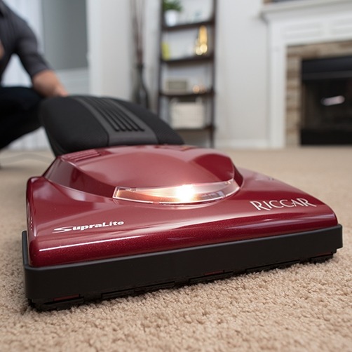 red vacuum laying flat on beige carpet